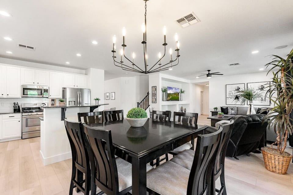 Elegant dining room with a modern chandelier and seating for eight, conveniently located off the living and kitchen areas.