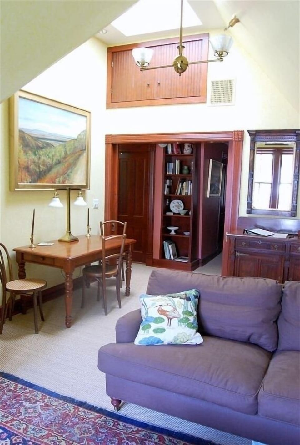 The airy sitting room has tall windows, a cathedral ceiling & a skylight.