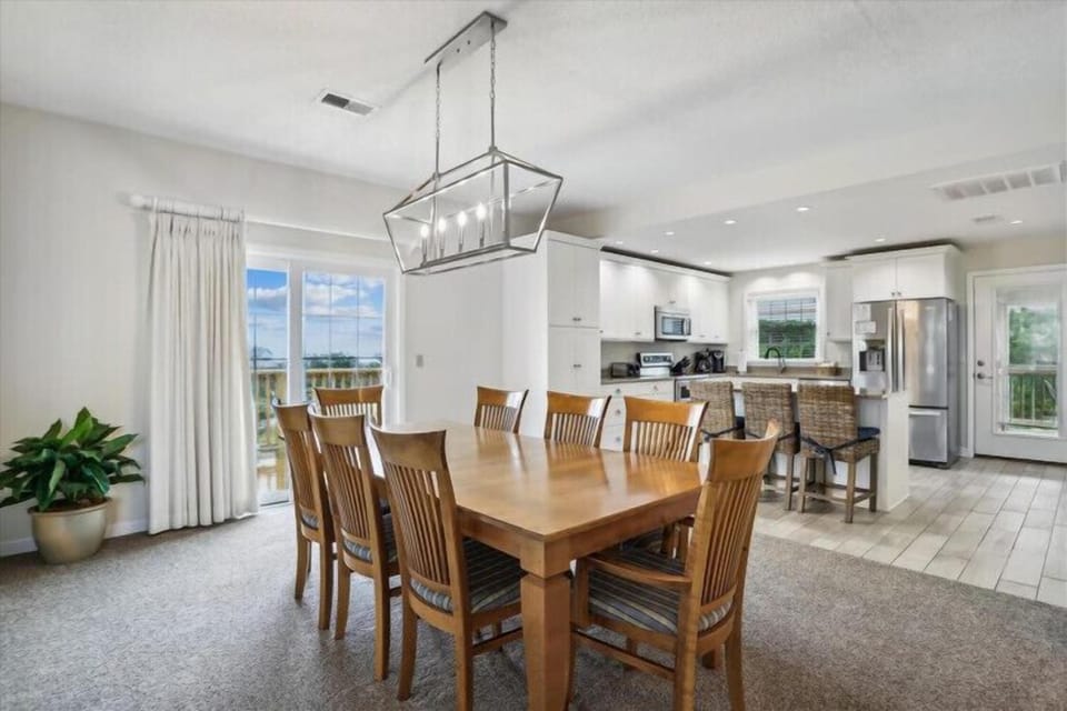 Step into your bright, open dining space where natural light pours through floor-to-ceiling windows. Gather around the spacious table with your group, enjoy meals in style, and relax knowing the full kitchen is steps away for easy entertaining.