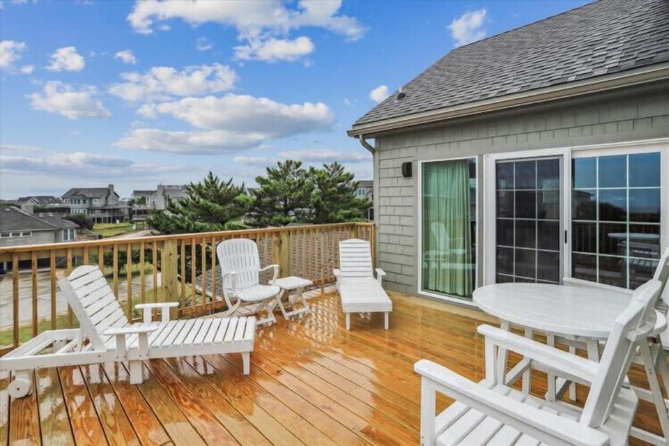 This spacious private deck overlooks a peaceful coastal neighborhood, with comfortable lounge chairs and dining space perfect for morning coffee or sunset gatherings.
