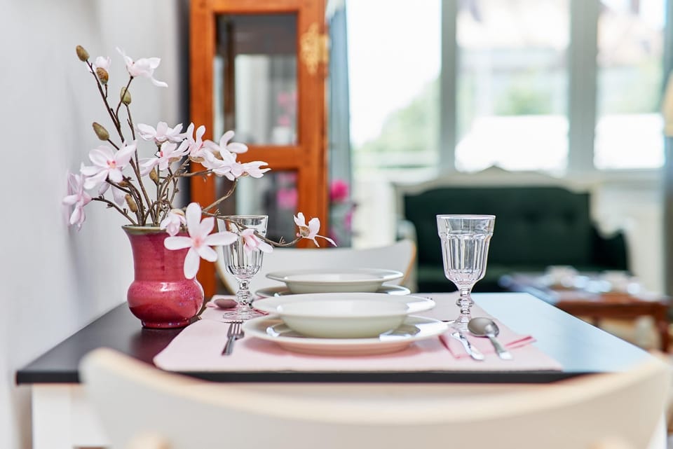 A dining table beautifully set with plates, glasses, and floral arrangements. The scene feels welcoming and ready for a meal.