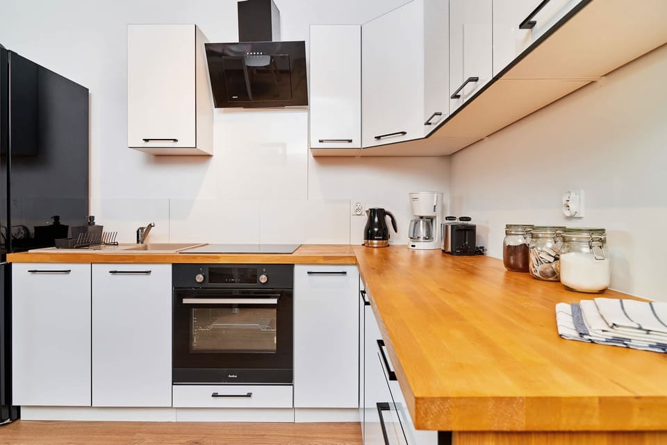 A sleek kitchen featuring white cabinetry and wooden countertops. The image emphasizes its functional layout and cleanliness.
