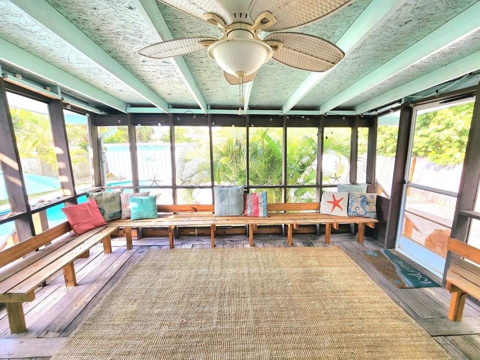 Screened-in porch with wrap-around seating and cozy pillows.