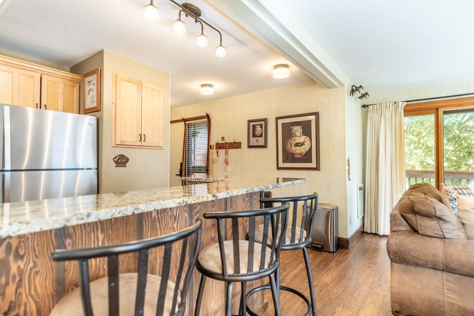 Gather around your spacious granite breakfast bar where mornings begin with coffee and conversation, perfectly positioned between the full kitchen and cozy living area.
