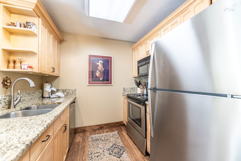 Your fully-equipped kitchen features granite counters, stainless appliances, and a skylight that fills the space with natural light for cooking.