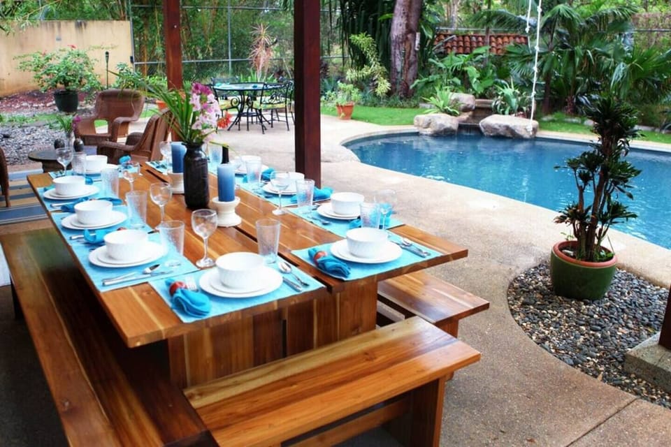 Charming outdoor dining area next to the pool, perfect for enjoying meals with family and friends while surrounded by tropical gardens and the relaxing sounds of nature.