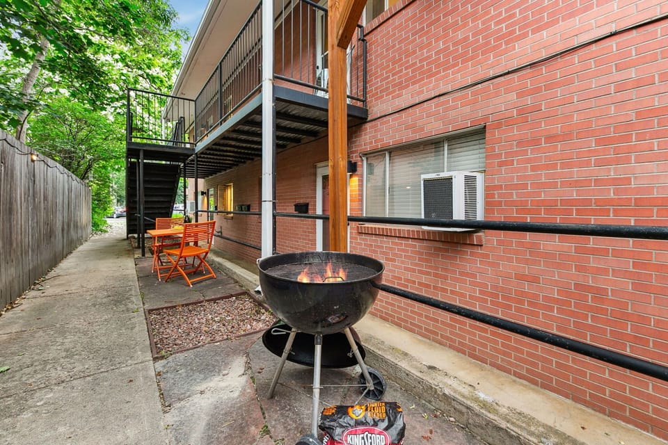 A cozy grilling area with string lights, charcoal grill, and bistro tables—perfect for outdoor meals!