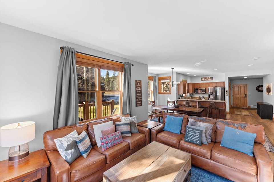 Sink into rich leather sofas while natural light streams through forest-facing windows in this open-concept living space with mountain views.