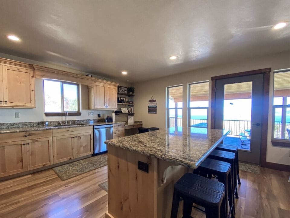 Bright, open kitchen with lake views, granite island seating, and easy access to the deck