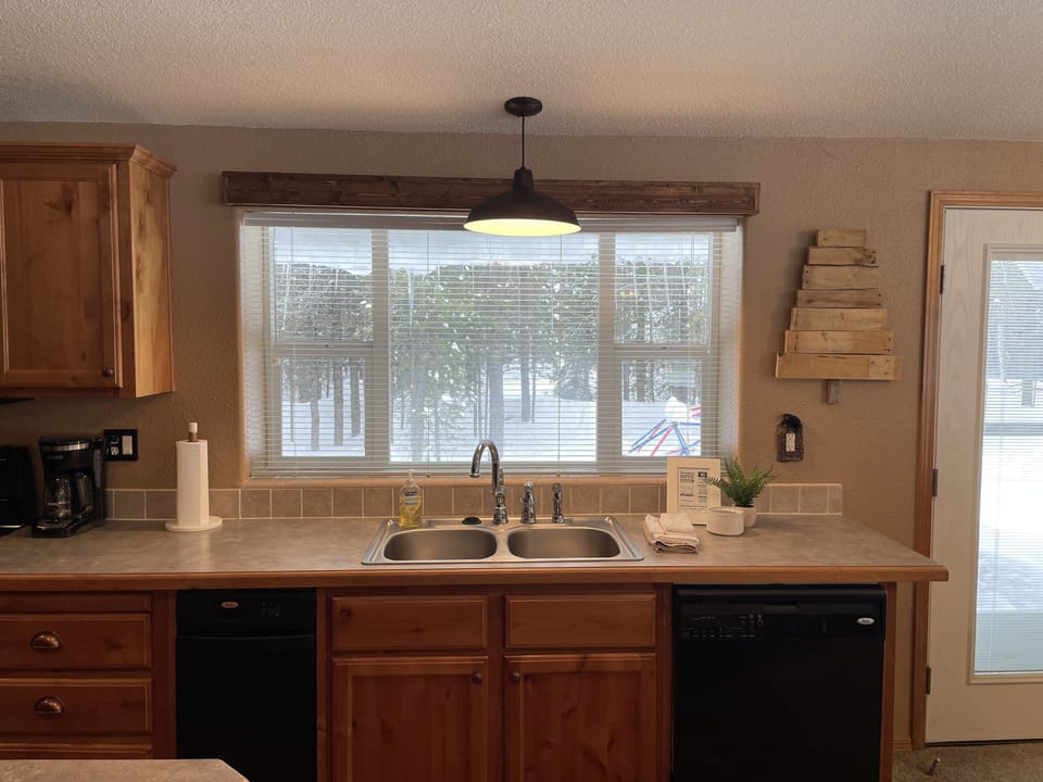 Large window over kitchen sink with a view of the yard and hot tub.
