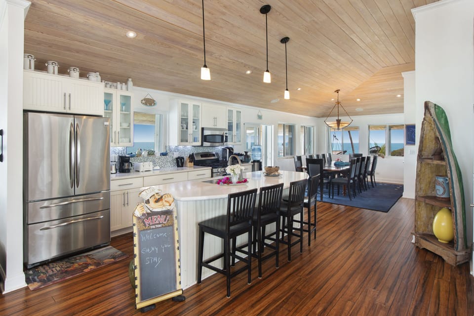 Full luxury kitchen with an oversized island with 4 bar stools, GE Profile appliances, and elegant quartz countertops.
