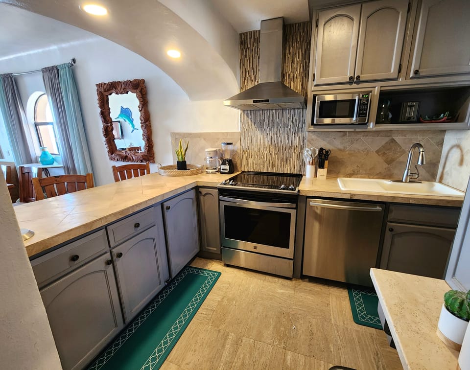 Kitchen area with basic cookware- kitchen appliances for guest use, and beautiful countertops with spacious and modern storage units.