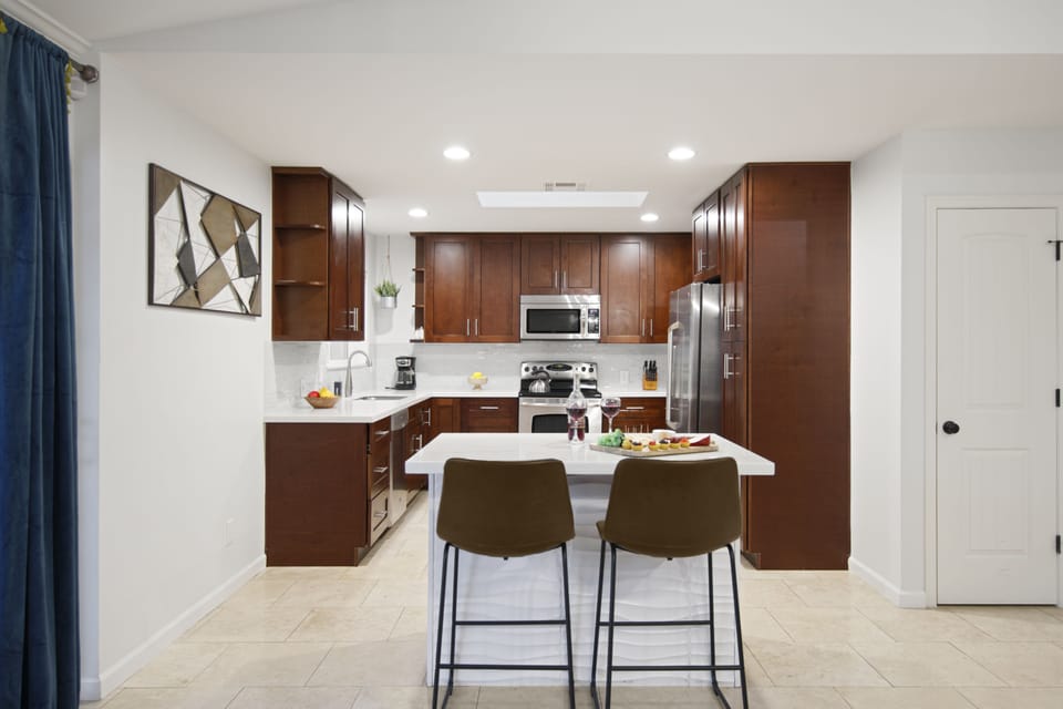 Fully-equipped kitchen with stainless steel appliances, complete with basic cooking essentials and island bar seating.
