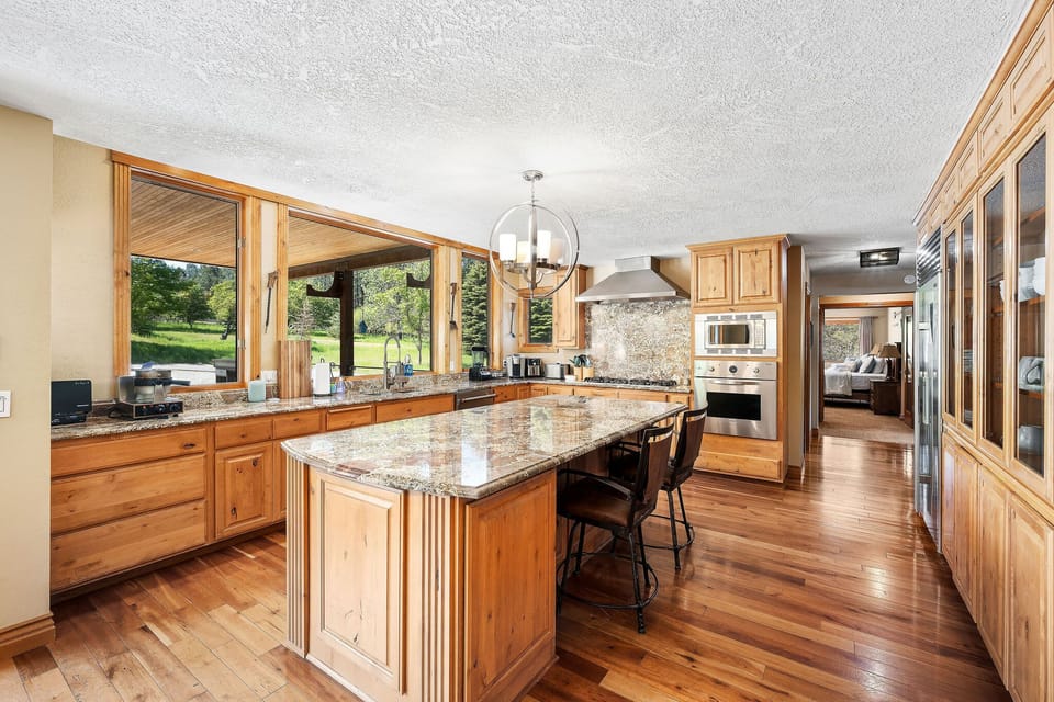 Cook in your gourmet kitchen with granite counters, warm wood cabinets, and scenic garden views through expansive windows.