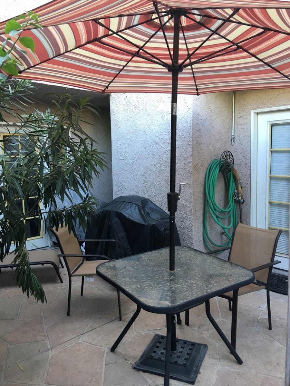 Patio with water fountain, bbq, lounge chair and dining set with umbrella.