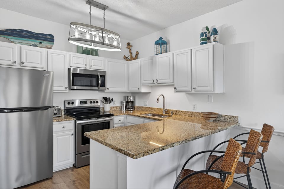 Your fully equipped kitchen awaits with granite counters, stainless appliances, and coastal charm—perfect for preparing meals in style.