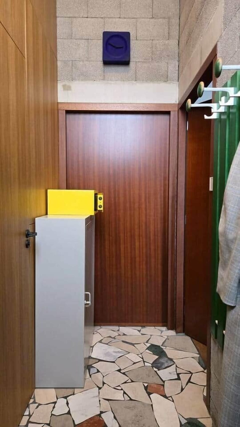 The hallway with a coat rack, entrance to the studio (right), and entrance to the bathroom (left).