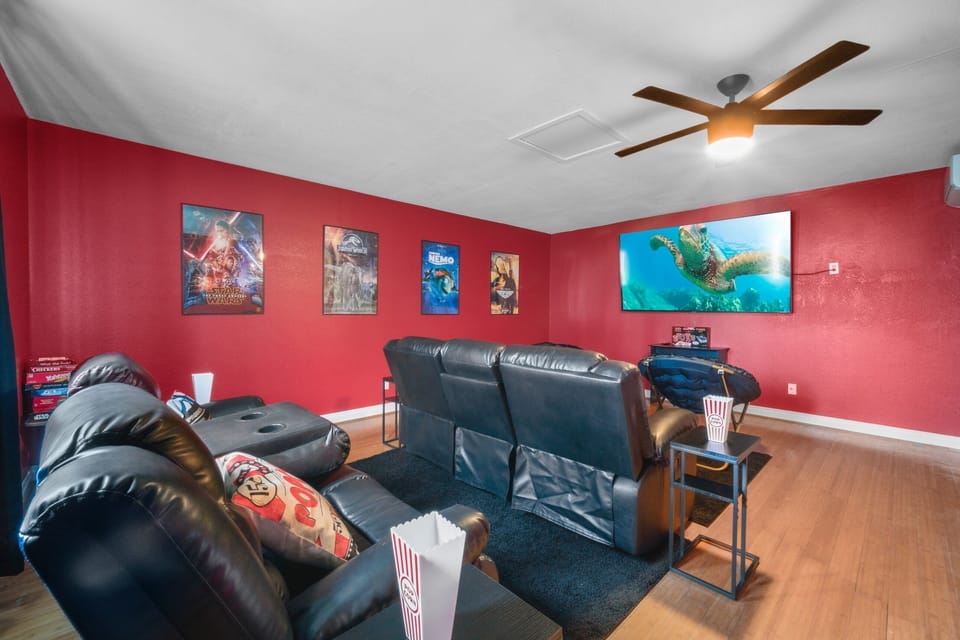 Living room with big screen, comfy black couch, perfect for movie nights.