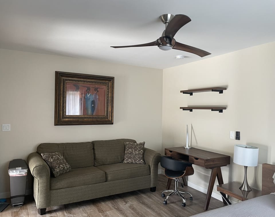 Desk area with table lamp and fabric couch. 