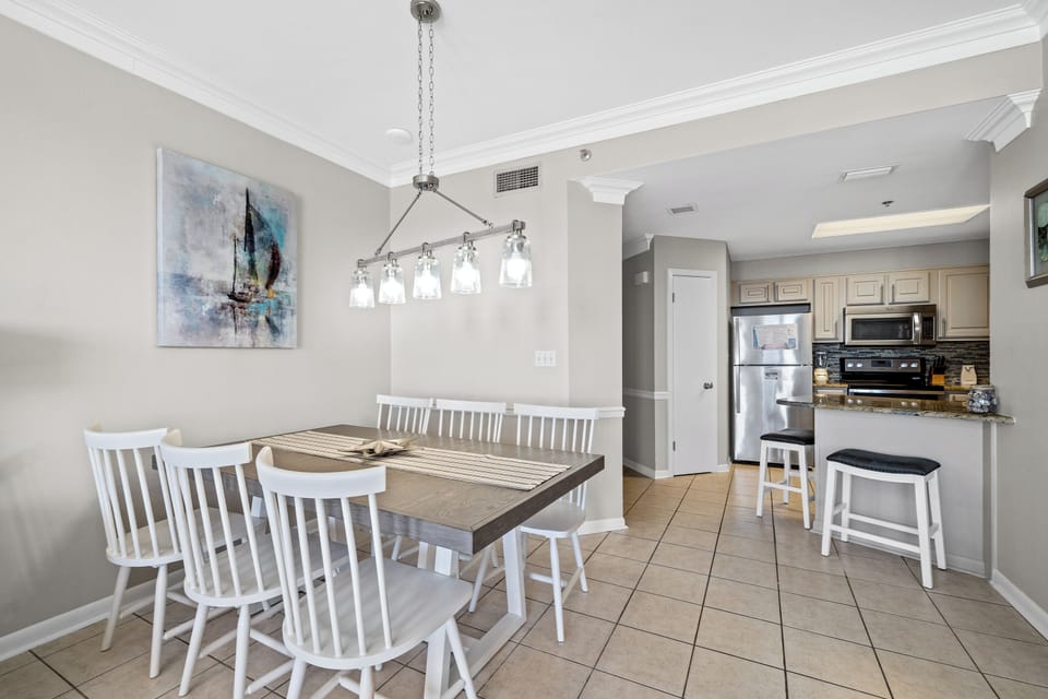 The dining area features a stylish table with white chairs, illuminated by a modern light fixture