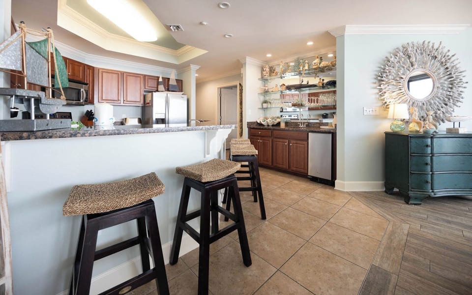 The kitchen features rich wood cabinetry, stainless appliances, and a stylish wet bar, perfect for entertaining