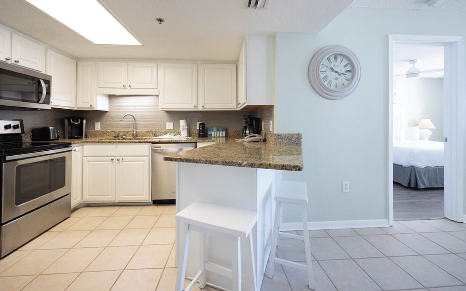 Kitchen featuring white cabinetry, granite countertops, coffee station, and a breakfast bar with stools