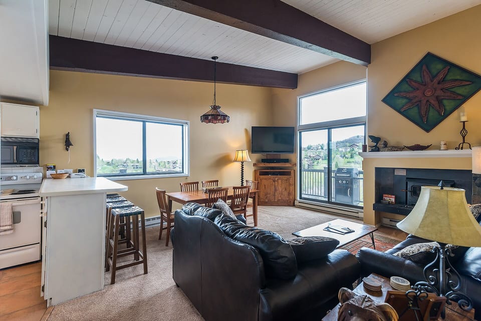 Unwind in your spacious open-concept retreat, where rustic beams frame mountain views and cozy seating invites relaxation by the fireplace.