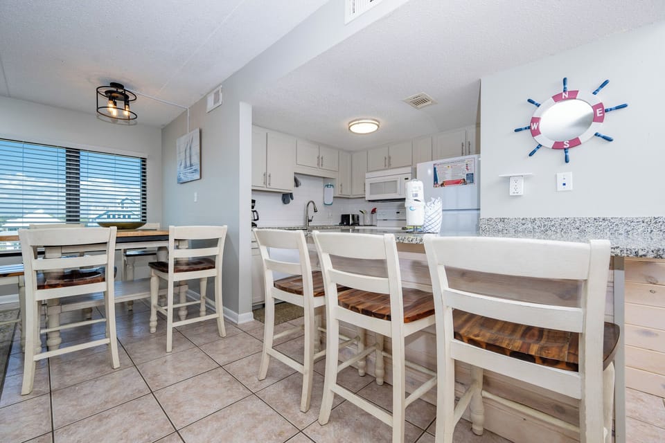 This inviting kitchen features a breakfast bar, sleek cabinetry, and view through large windows