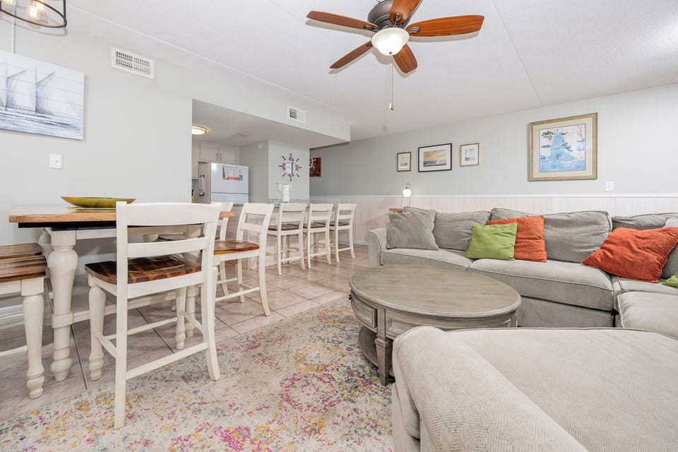 The condo features a comfortable sectional sofa, stylish coffee table, and dining space, perfect for relaxation