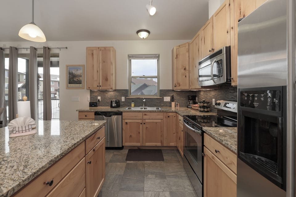 Your fully-equipped kitchen awaits with granite counters, stainless appliances, and warm wood cabinets—perfect for preparing memorable meals together.