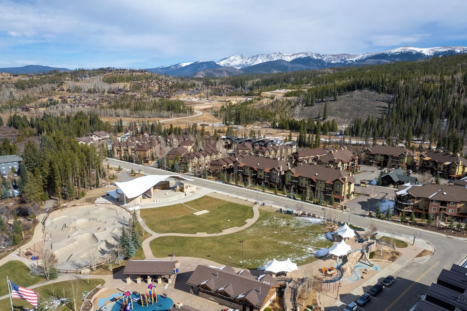 Aerial view of a mountain resort community nestled among snow-capped peaks and evergreen forests, offering scenic alpine surroundings.