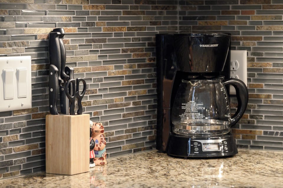 Wake up to the aroma of fresh coffee brewing in your fully equipped kitchen, complete with modern appliances and stylish tile backsplash.