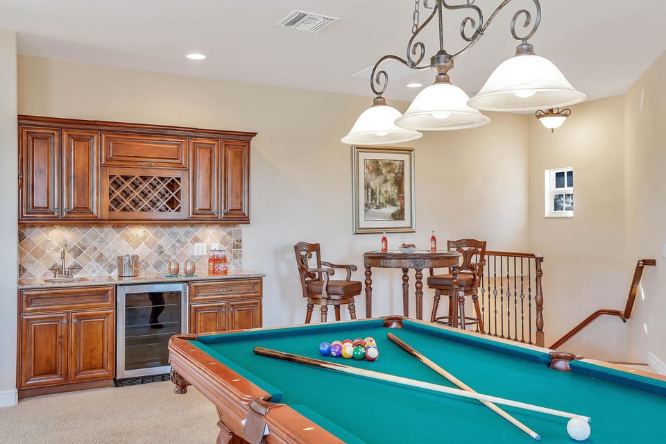 The separate Games Room is set on the upper level of the home with a wet bar and full bathroom + balcony overlooking the pool deck.