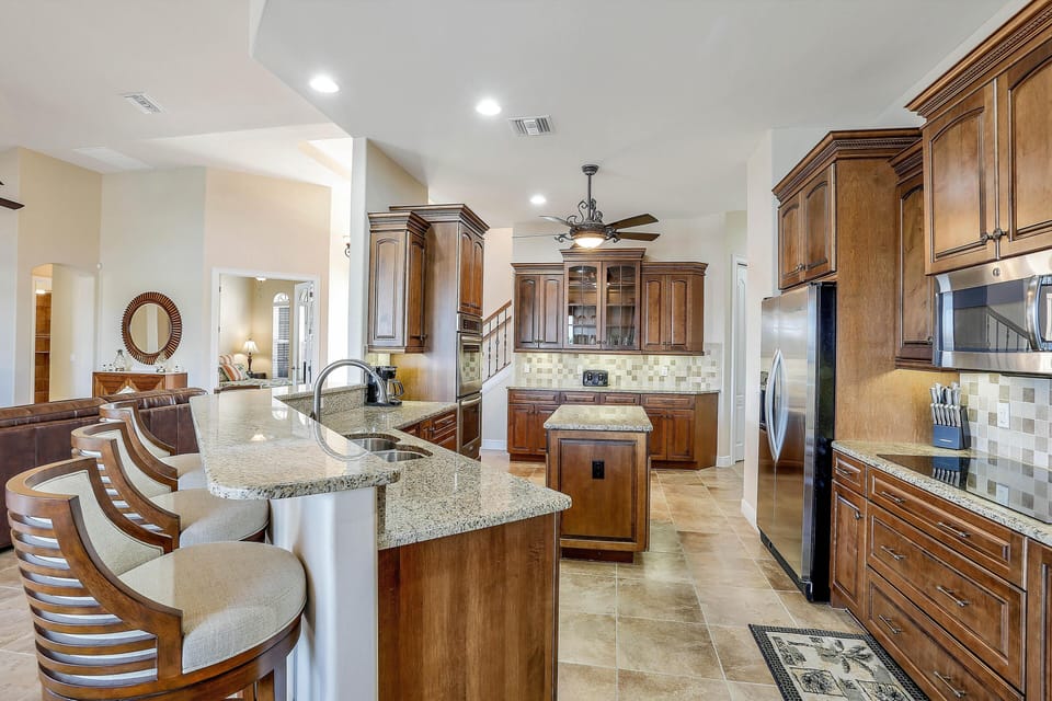 The large open plan Kitchen with granite countertops stretching across the kitchen island and breakfast bar with stainless steel appliances.