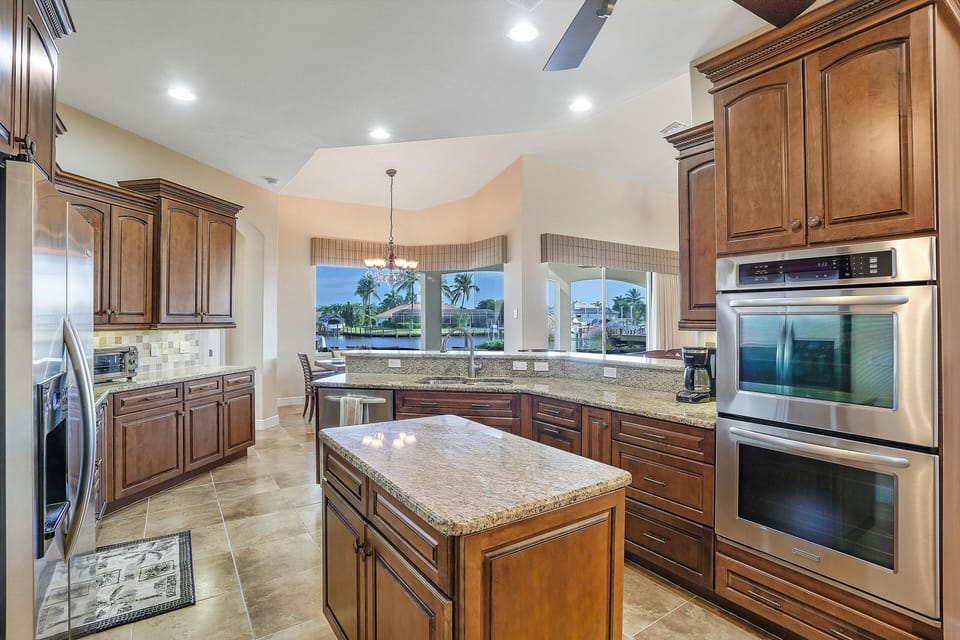 Large open plan Kitchen with granite countertops cover the kitchen island.  Stainless double oven and a side-by-side refrigerator.