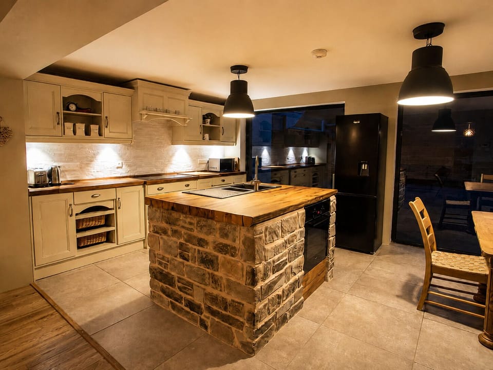 Rustic-chic kitchen with stone island, warm lighting, and spacious layout