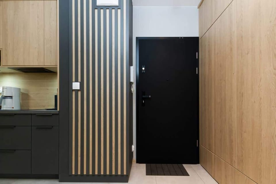 The entrance area of an apartment unit, featuring sleek, dark doors and a modern wall panel design for a sophisticated look.