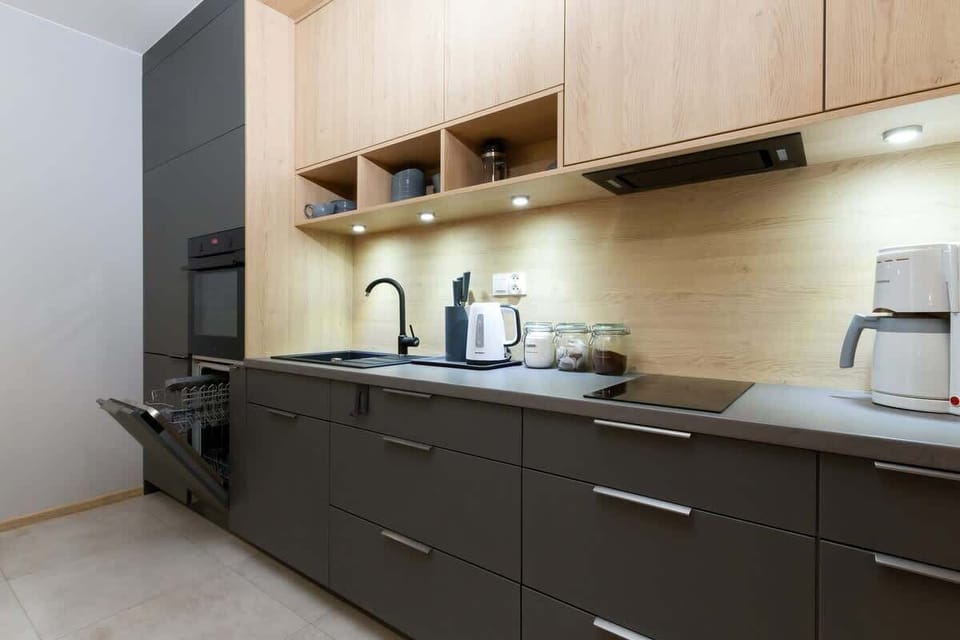 A sleek and modern kitchen with dark cabinets, built-in appliances, and a bright backsplash. There is a small counter space for food preparation.