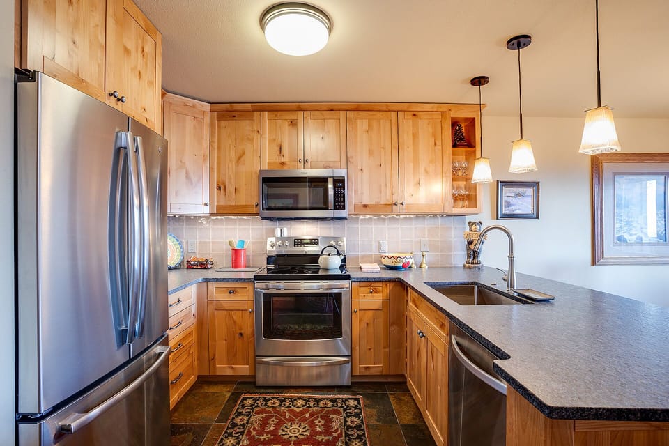 Your fully equipped kitchen features warm wood cabinetry, granite countertops, and modern appliances for memorable meal preparation.