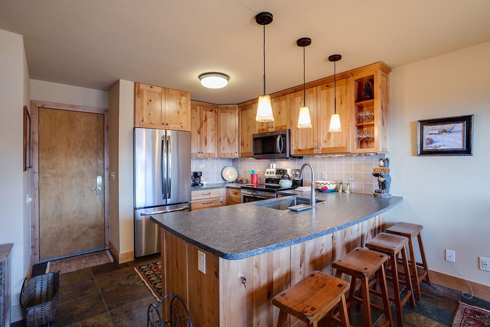 Your fully equipped kitchen awaits with warm wood cabinets, granite counters, and a breakfast bar perfect for morning coffee.
