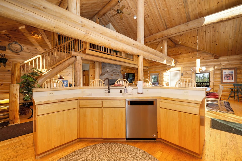 Your rustic log cabin kitchen features modern appliances and soaring ceilings that create an airy, mountain retreat atmosphere for memorable meals.