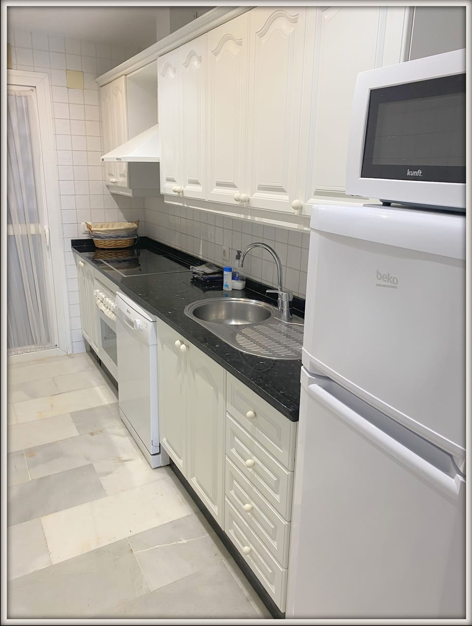Fully equipped kitchen leading to utility area with washing machine