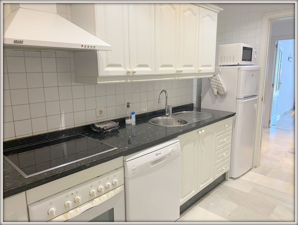 Fully equipped kitchen leading to utility area with washing machine
