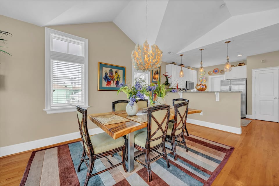 Gather around this inviting dining table under a stunning statement chandelier. The open-concept space flows into a bright kitchen, perfect for sharing meals and making memories together.