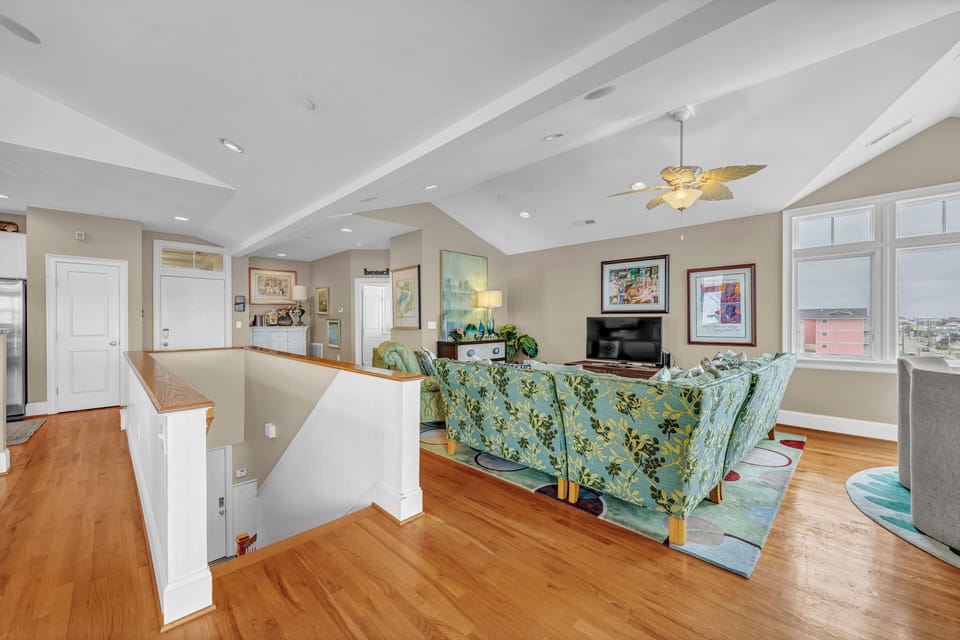 Relax in your bright, open living room with vaulted ceilings, coastal charm, and windows overlooking the surrounding area—perfect for unwinding after a day of adventure.