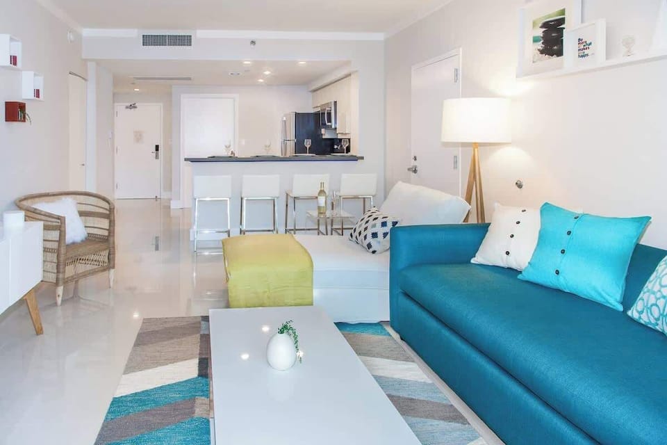 View of the living room and the main kitchen in the background. Large, well lit.