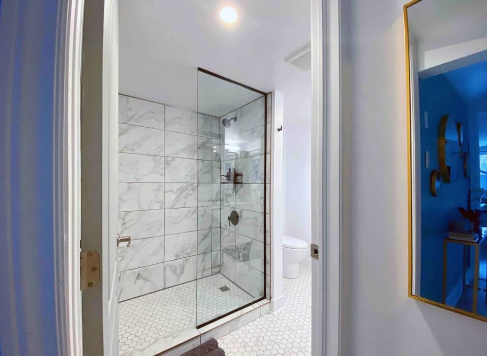 Full bathroom with walk in shower, toilet, toilet paper, sink, towels, hairdryer