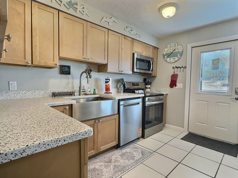 Kitchen view showing peninsula counter, stainless appliances, and tile floor