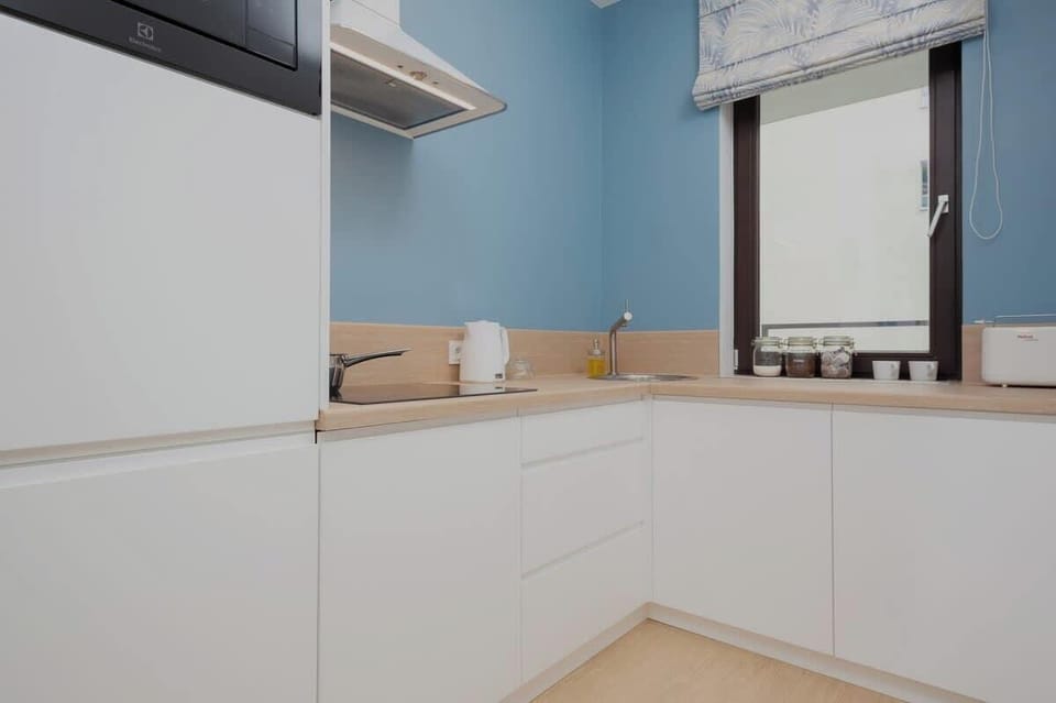 A modern kitchen with light blue walls, white cabinets, and wooden countertops, offering a clean and functional space.