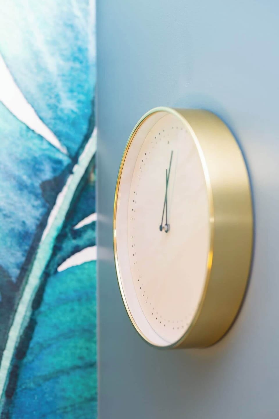 A close-up of a unique, modern golden clock hanging on a wall.